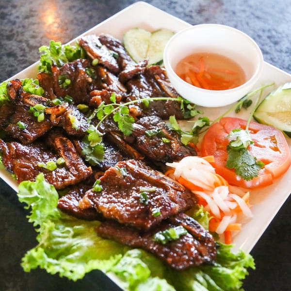 Vietnamese grilled short ribs with lettuce, pickled vegetables, tomato, cucumber, and dipping sauce.